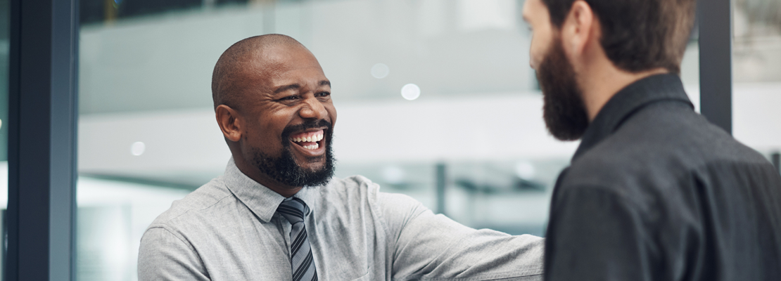 Smiling Black financial services provider in Ottawa welcoming a client to his office.