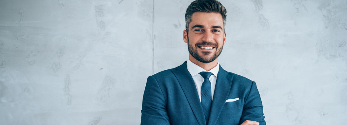 A management consultant dressed in a blue suit smiling at the camera.